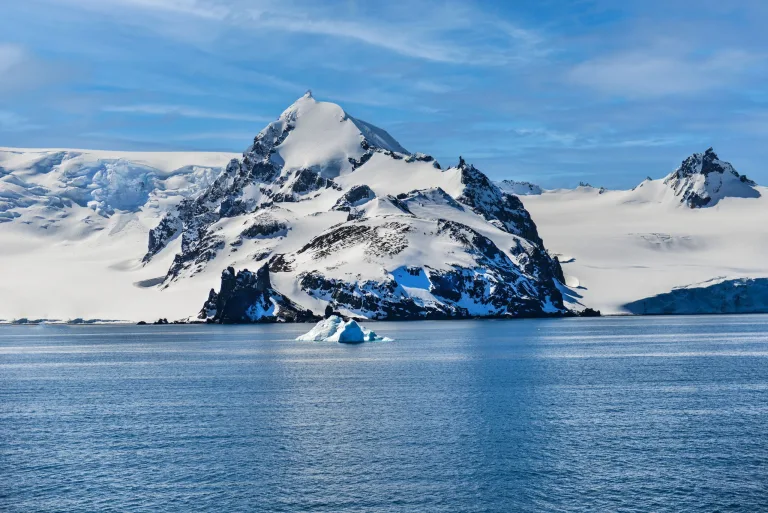 Pico nevado e iceberg, península Antártica